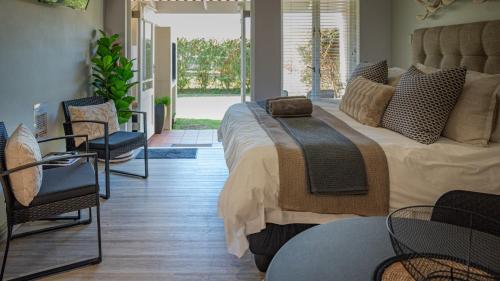 a bedroom with a large bed with chairs and tables at The Dunes Haven studio in Keurboomstrand