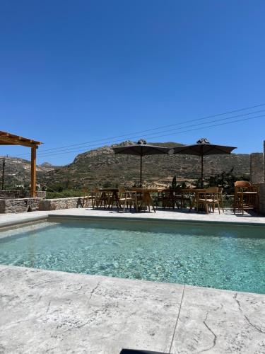 a swimming pool with tables and chairs and umbrellas at Ninemia Naxos Suites in Naxos Chora