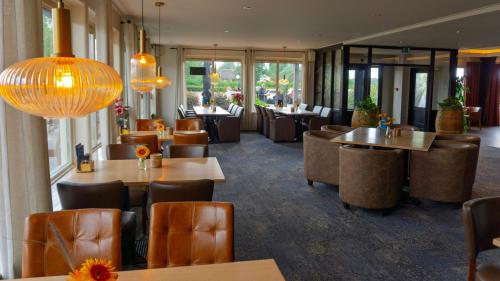 a restaurant with tables and chairs and windows at Hotel de Harmonie in Giethoorn