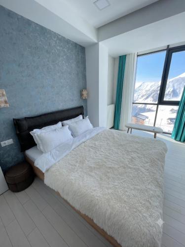 a bedroom with a large bed with a large window at winter house GUDAURI in Gudauri