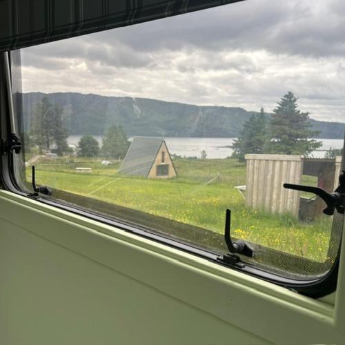 a window with a view of a field and a house at the buttercup shed in Lochcarron