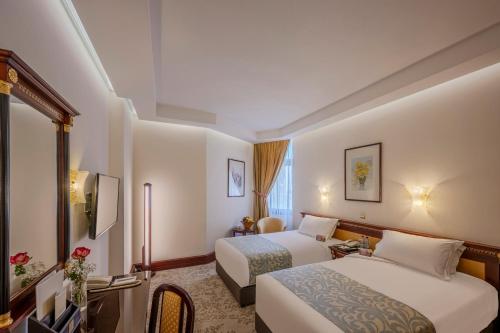 a hotel room with two beds and a desk at Al Shohada by Palm Rich Makkah in Mecca