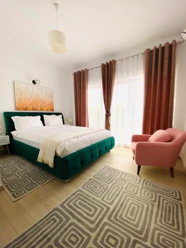 a bedroom with a large bed and a pink chair at Debres Apartment Aiud in Aiud
