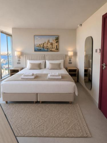 a bedroom with a large white bed and a large window at Sliema Centric Hotel in Sliema