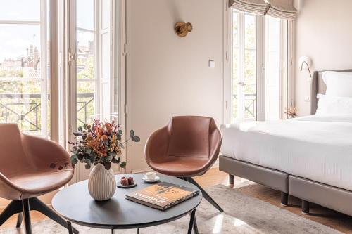 a bedroom with a bed and two chairs and a table at Villas Foch Boutique Hotel & Spa Bordeaux in Bordeaux