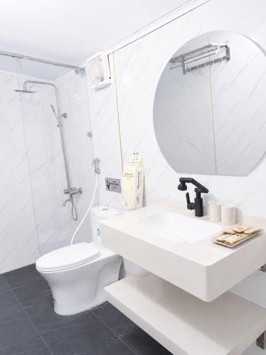 a white bathroom with a toilet and a sink at Kingfisher Nest in Hai Phong