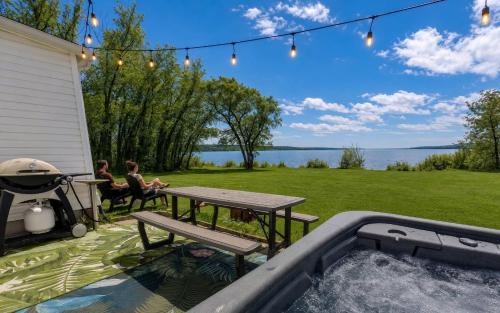 a patio with a table and a picnic table and a grill at Condo 1 - Waterfront with SPA, Fireplace & Barbecue in Sainte-Anne-de-Beaupré
