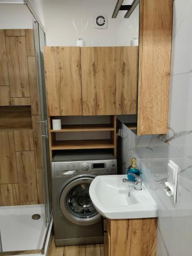 ein kleines Badezimmer mit Waschmaschine und Waschbecken in der Unterkunft APT w centrum in Suwałki