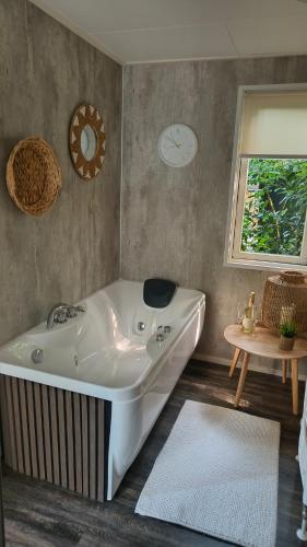a bath tub in a bathroom with a clock on the wall at Bos & Bubbels Chalet in Epe