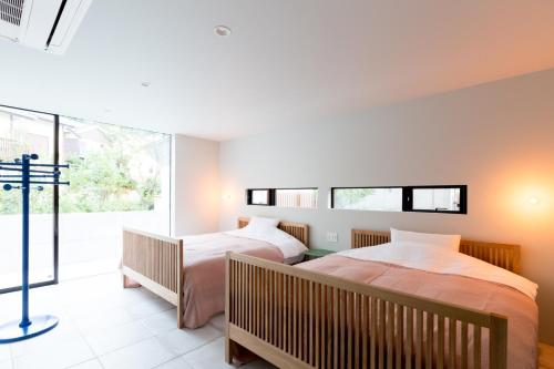 twee bedden in een kamer met een raam bij The Canvas Hayama Park in Hayama