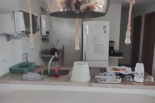 a kitchen counter with a sink and a refrigerator at Porto bello condomínio in Porto De Galinhas