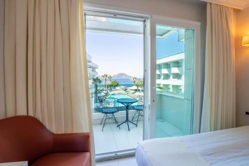 a bedroom with a bed and a glass door leading to a balcony at Dragut Point South Hotel-All Inclusive in Turgutreis