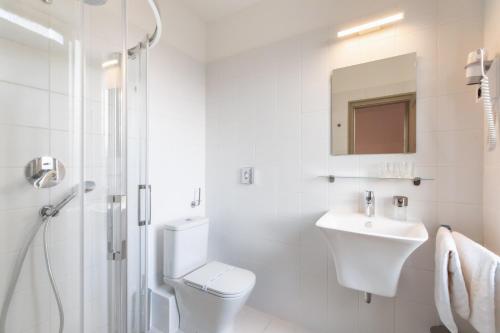 a white bathroom with a toilet and a sink at Mr Görgey Art Hotel in Visegrád