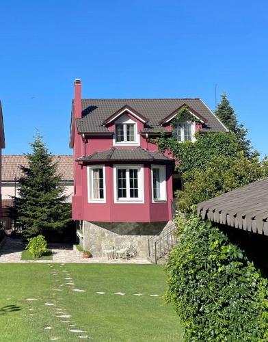 a pink house with white windows on a yard at Tre Bujtinat Gjinar in Elbasan