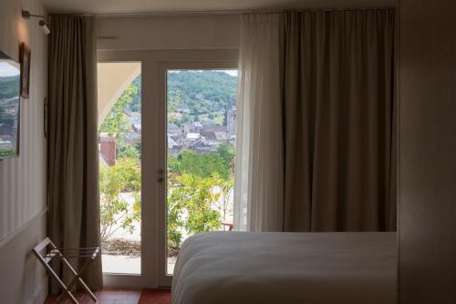 a bedroom with a bed and a large window at Hôtel Maison Borrèze in Souillac