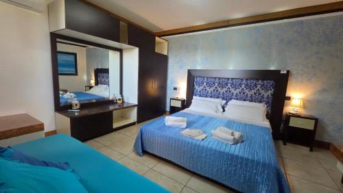 a bedroom with a blue bed and a mirror at Hotel Alba Chiara Sant'Andrea Salento in SantʼAndrea