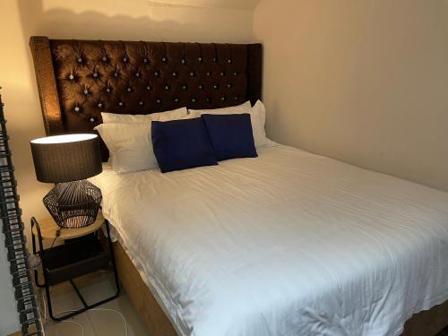 a bedroom with a large bed with blue pillows at Nais cottage in Cape Town