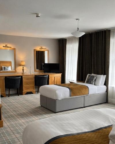 a hotel room with two beds and a desk at Fairhill House Hotel in Clonbur