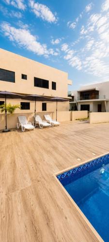 a patio with chairs and a swimming pool on a building at Executive Cozy Suite at THE HIDDEN DOMUS I Wenchi Suite in Accra