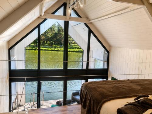 a large window in a room with a bed and a view of the water at Les Kabanes de Kerforn in Crach