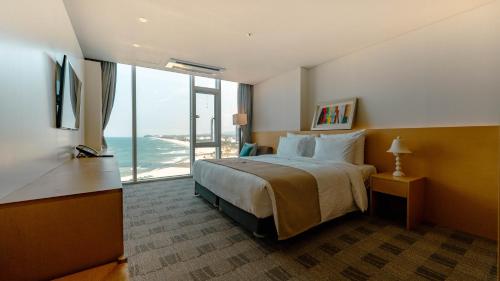 a hotel room with a bed with a view of the ocean at Potalaka Naksan Beach Wellness in Yangyang