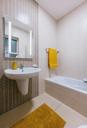 a bathroom with a sink and a tub and a mirror at Sunny 2 BR Aptm with Garden Fast WiFi Walk to Seafront in Il-Gżira