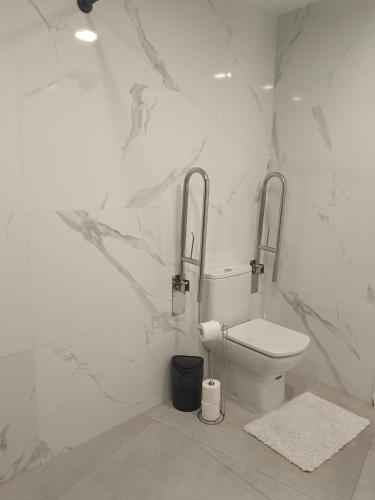 a white bathroom with a toilet and marble walls at Edificio Mañez - Bajo in La Línea de la Concepción