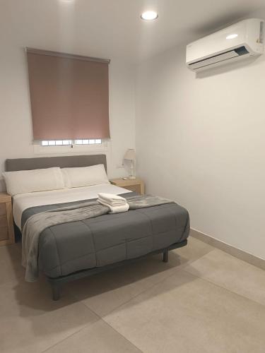 a bedroom with a bed and a air conditioner at Edificio Mañez - Bajo in La Línea de la Concepción