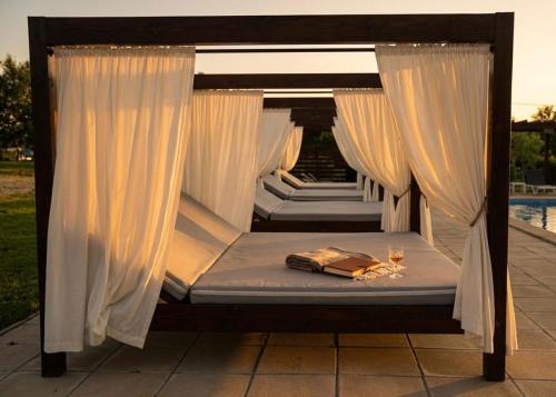 a canopy bed with white curtains and wine glasses at Casa Vlasia in Snagov