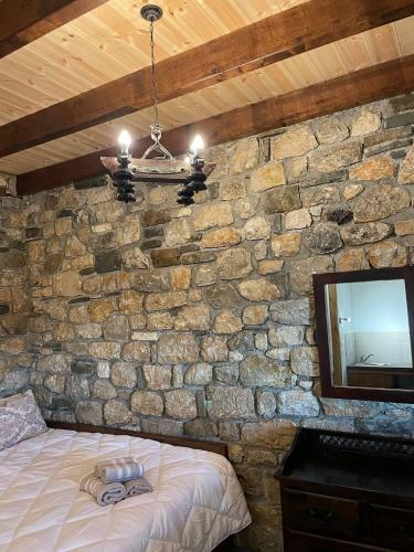 a bedroom with a stone wall with a bed and a television at Villa Lochia - Το Πέτρινο του Θωμά in Rámia