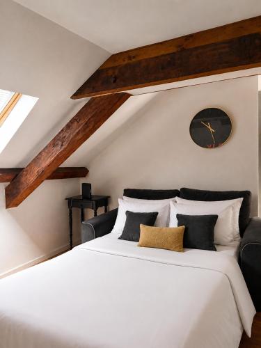 a bedroom with a large white bed with a clock on the wall at le petit château in Chambéry