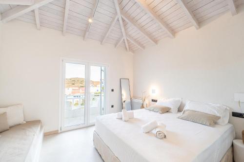 a white bedroom with a large bed and a window at Drio Kythnos Suites in Dhriopís
