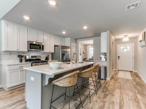 a kitchen with white cabinets and a large island with bar stools at Spacious Retreat with Vaulted Ceilings & Primary Suite! in Broken Arrow