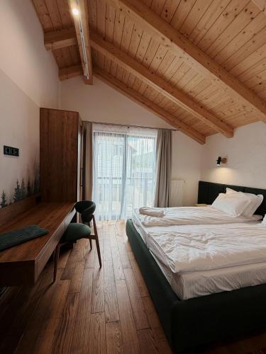 a bedroom with a bed and a desk and a window at Альпійські шале Душа in Palyanytsya