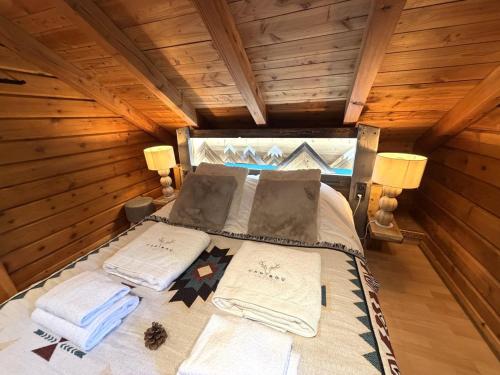 a bed in a log cabin with towels on it at LE GRIZZLY Chalet en bois avec SPA Jacuzzi in La Bresse