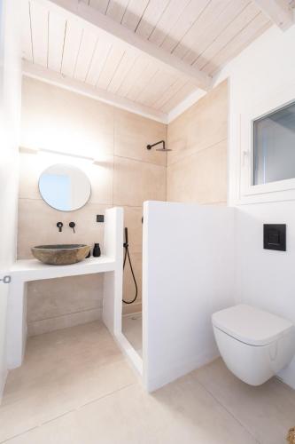 a white bathroom with a sink and a toilet at Drio Kythnos Suites in Dhriopís