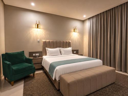 a bedroom with a bed and a green chair at Eliana Hotel in Al Khobar