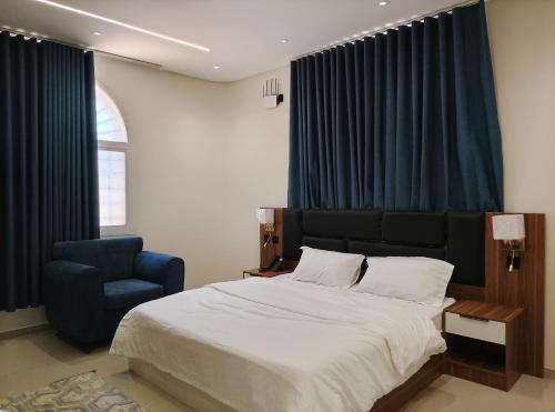 a bedroom with a large bed and a blue chair at شاليهات المروان لبيوت العطلات - AL-Marwan for Holiday Homes in Ash Shafa