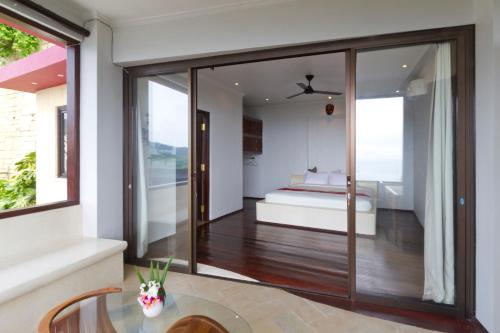 a bedroom with a bed and a glass door at Villa Umbrella Lombok in Senggigi 