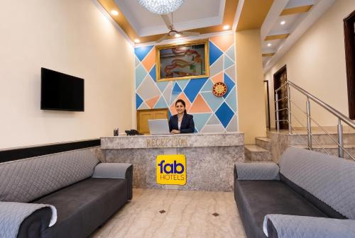 a woman sitting at a reception desk with a laptop at FabHotel Le Sancy in New Delhi