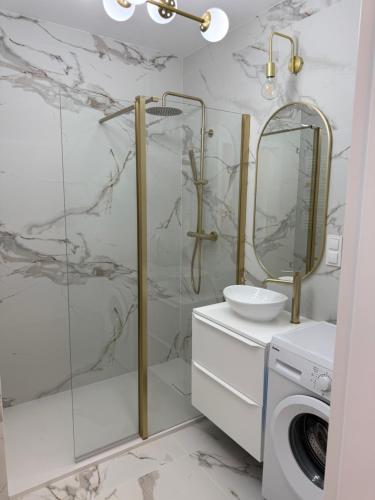 a bathroom with a shower and a sink and a washing machine at Apartament Cysterski Pelplin in Pelplin