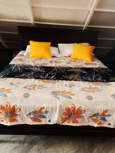 a bed with yellow pillows and a comforter at Mount Homestay in Nedukandam