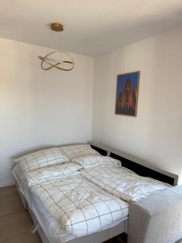 a bed in a white room with a picture on the wall at Apartament Cysterski Pelplin in Pelplin