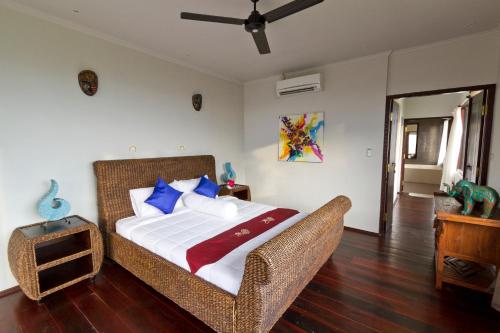 a bedroom with a bed and a wicker chair at Villa Umbrella Lombok in Senggigi 