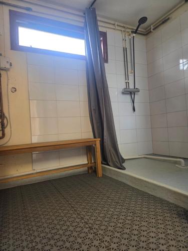a shower room with a bench and a window at Ofvansjö Gård , Enkel stuga för övernattning på ett fd militärområde in Sandviken
