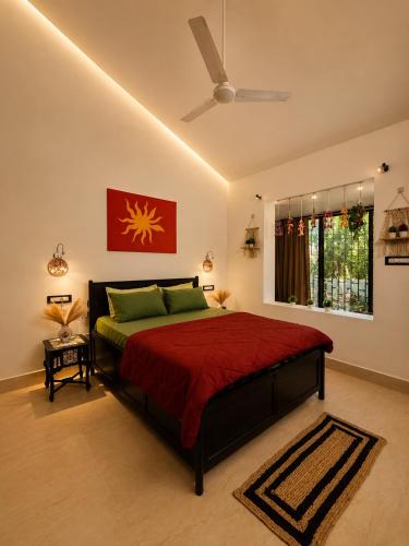 a bedroom with a bed with a red comforter and a window at Coconut Sky 2Bhk Penthouse Baga in Baga