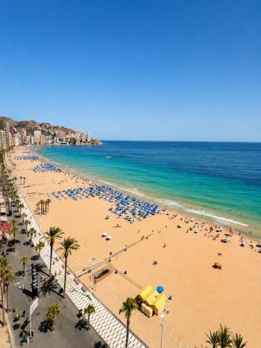 a beach with many umbrellas and the ocean at Apartamento Benidorm primera linea in Benidorm