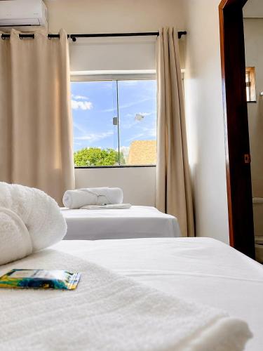 two beds in a room with a window at Kuri Hotel in Padre Bernardo