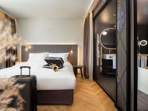 a hotel room with a bed and a suitcase at Hotel Am Konzerthaus - MGallery Collection in Vienna
