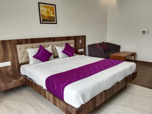 a bedroom with a large bed with purple pillows at Tech City Hotel Trivandrum in Trivandrum